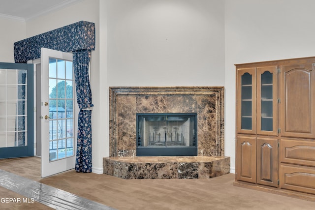 carpeted living area featuring ornamental molding and a premium fireplace