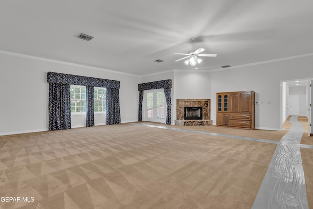 unfurnished living room with visible vents, crown molding, ceiling fan, light colored carpet, and a premium fireplace