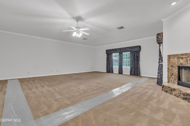 unfurnished living room with a ceiling fan, visible vents, crown molding, a high end fireplace, and carpet flooring