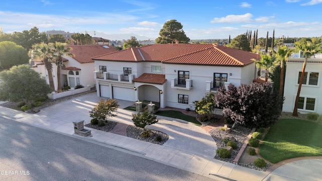 mediterranean / spanish house featuring driveway, a tile roof, a balcony, an attached garage, and stucco siding