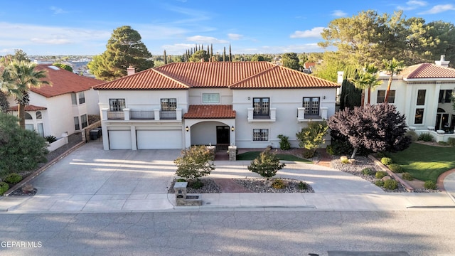 mediterranean / spanish-style house with a tiled roof, driveway, a garage, a balcony, and stucco siding