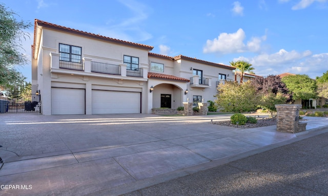 mediterranean / spanish-style home with an attached garage, stucco siding, a balcony, and driveway