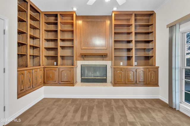 unfurnished living room with baseboards, carpet flooring, a glass covered fireplace, and a ceiling fan
