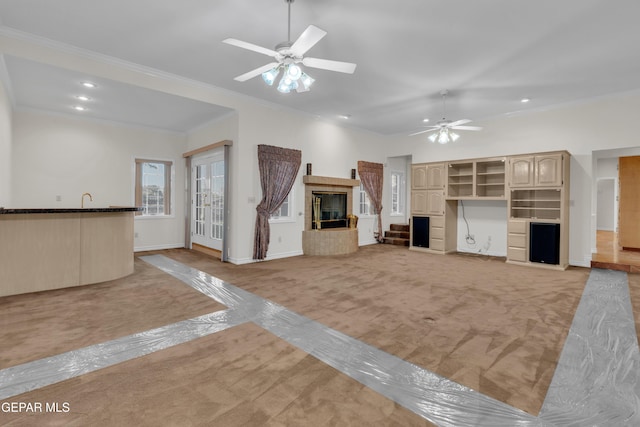 unfurnished living room with a tiled fireplace, baseboards, ceiling fan, and crown molding