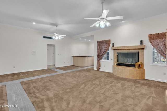 unfurnished living room with a tiled fireplace, ceiling fan, and carpet floors