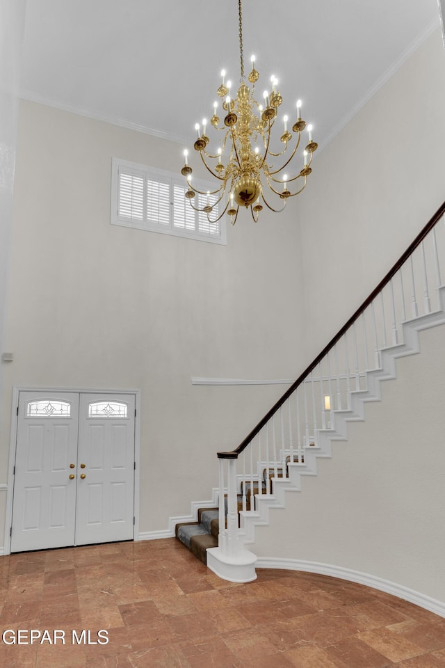 foyer entrance with crown molding, stairs, a chandelier, and a towering ceiling