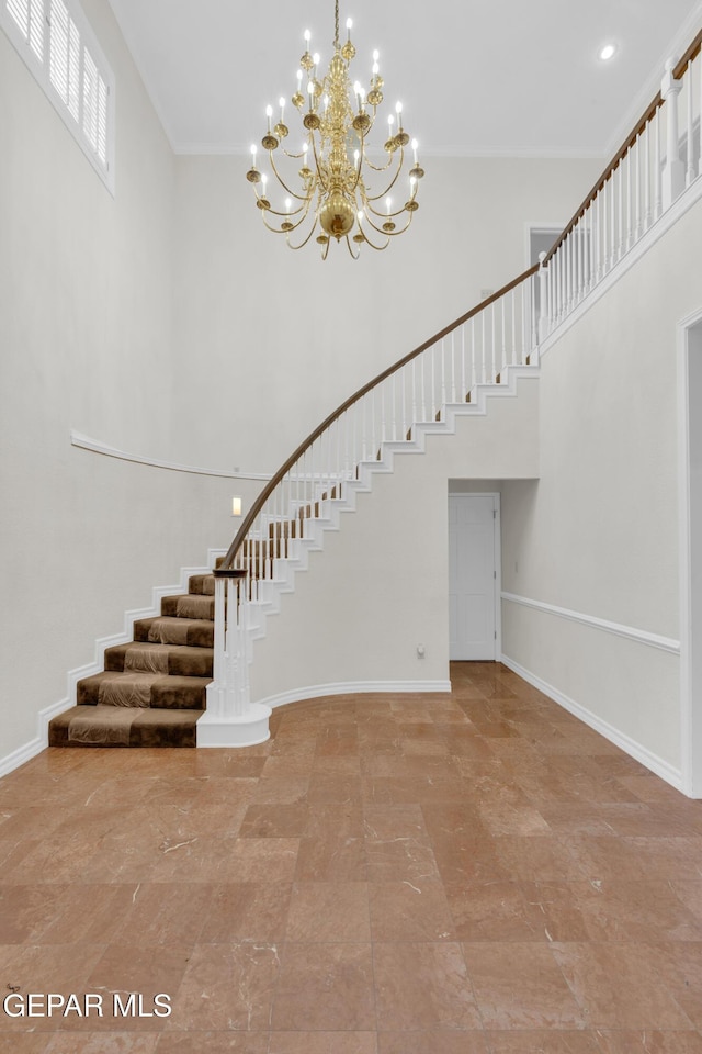 stairs featuring a high ceiling, a chandelier, ornamental molding, and baseboards