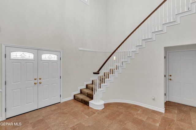 entrance foyer with baseboards, a high ceiling, and stairs