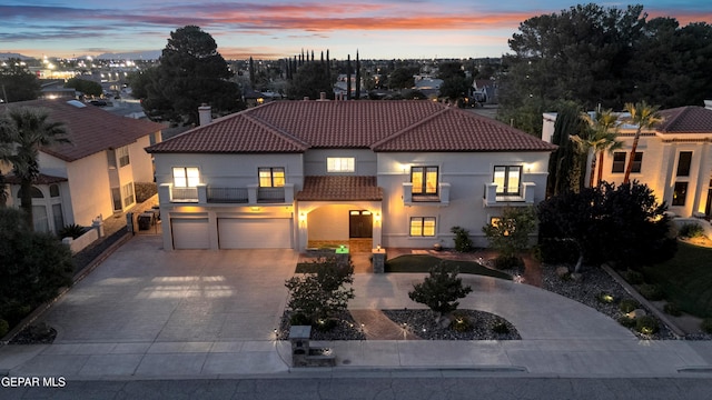 mediterranean / spanish-style house with a tile roof, a garage, a chimney, a balcony, and curved driveway