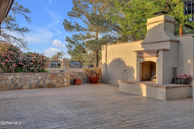 view of patio / terrace featuring an outdoor stone fireplace and fence