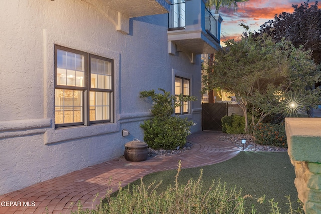 view of home's exterior with fence, stucco siding, and a balcony