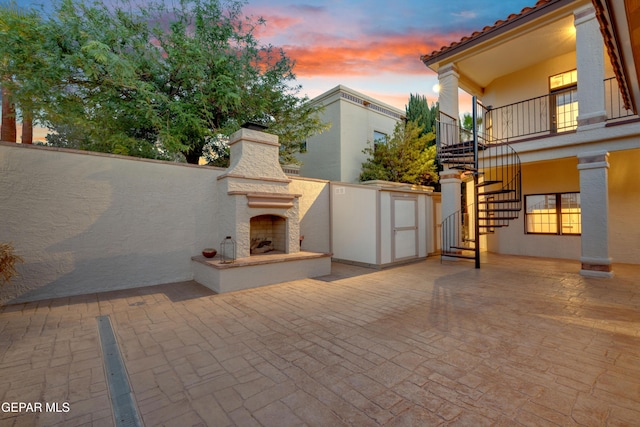 patio terrace at dusk with stairway and exterior fireplace
