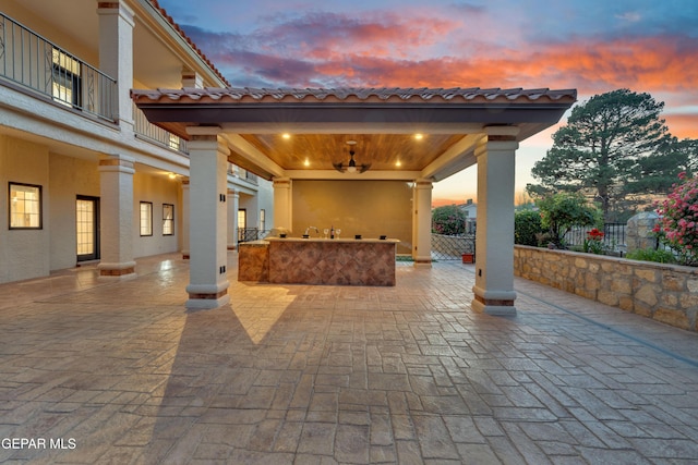 patio terrace at dusk with a gazebo, fence, and exterior bar