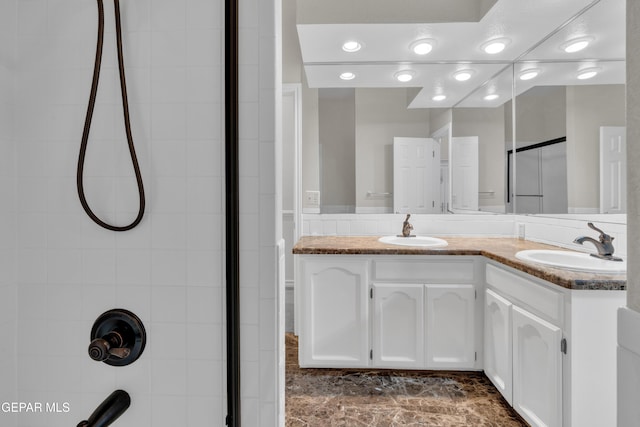 full bath featuring double vanity, a sink, and a shower with shower door