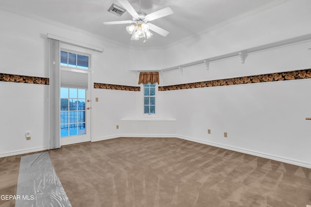 empty room with carpet flooring, crown molding, ceiling fan, baseboards, and visible vents