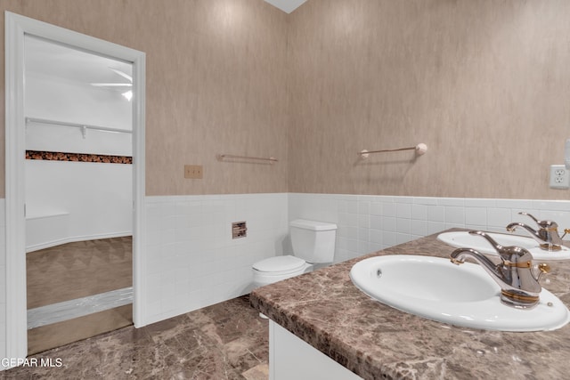 full bathroom featuring toilet, tile walls, wainscoting, and vanity