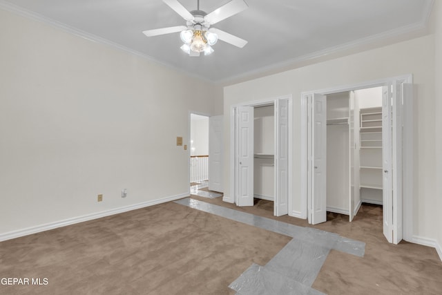 unfurnished bedroom with carpet floors, multiple closets, crown molding, and baseboards