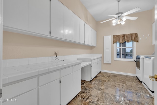 laundry area featuring baseboards, a ceiling fan, cabinet space, and washer and clothes dryer