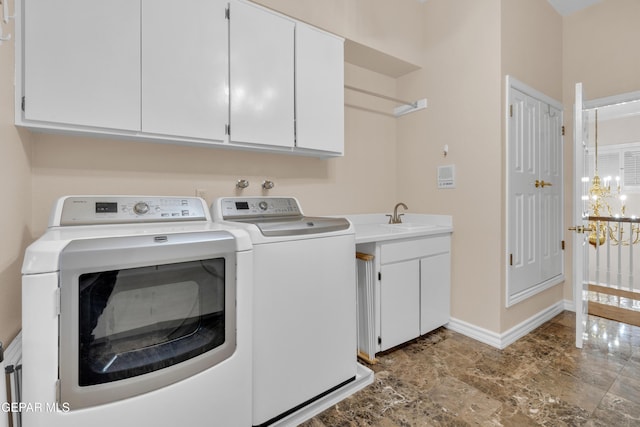 clothes washing area featuring washing machine and dryer, cabinet space, a sink, baseboards, and a chandelier