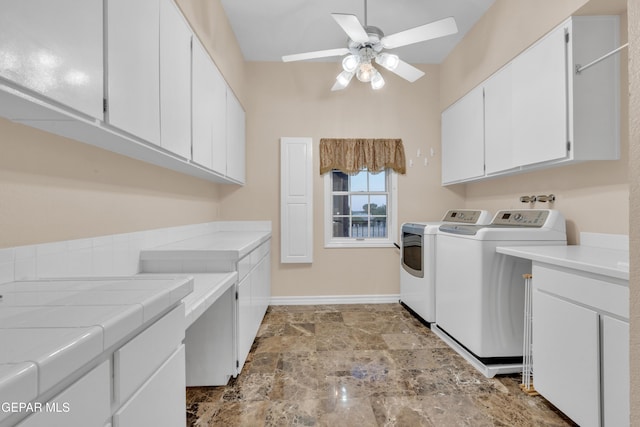 laundry area with cabinet space, a ceiling fan, baseboards, stone finish flooring, and washing machine and dryer