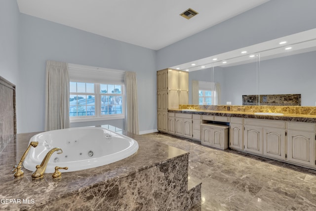 bathroom with visible vents, plenty of natural light, a jetted tub, and vanity