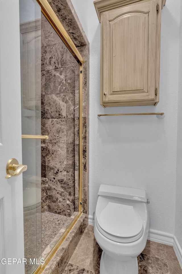 full bathroom featuring toilet, baseboards, and a shower stall