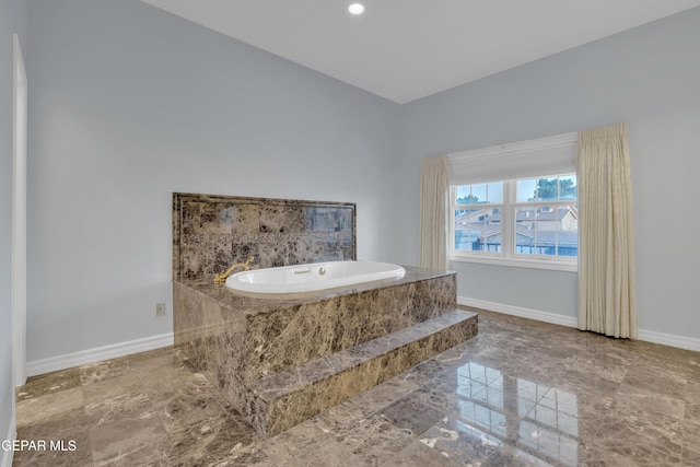 bathroom with recessed lighting, baseboards, and a bath