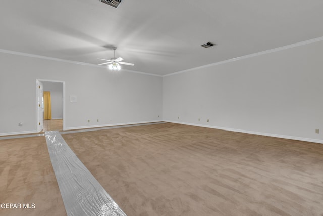 empty room with crown molding, ceiling fan, visible vents, and light carpet