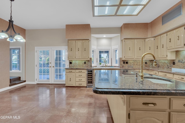 kitchen with beverage cooler, a sink, dark stone countertops, backsplash, and hanging light fixtures