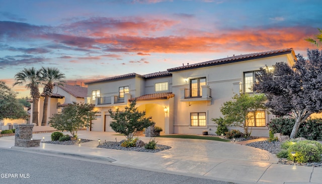 mediterranean / spanish-style home with a garage, a balcony, stucco siding, concrete driveway, and a tile roof