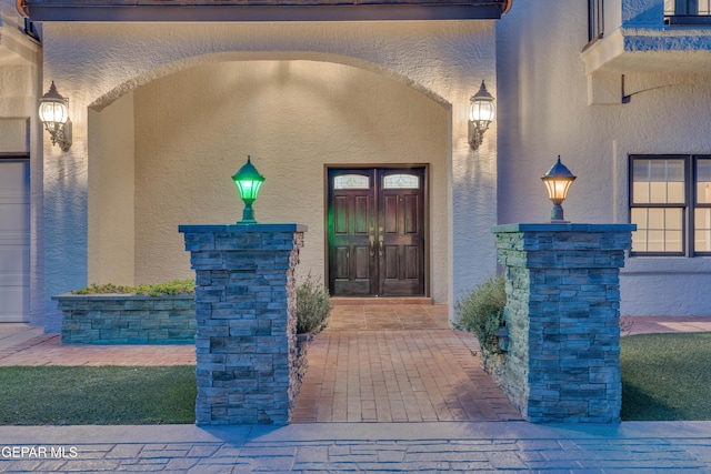 doorway to property featuring stucco siding and stone siding