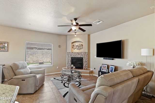living area featuring visible vents, light tile patterned floors, baseboards, a fireplace, and ceiling fan