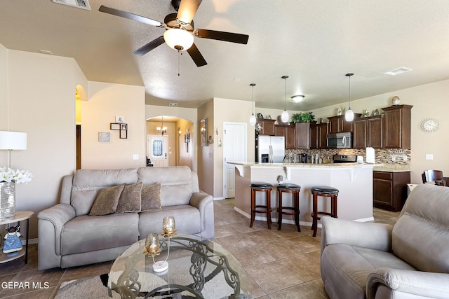 living area with a ceiling fan, visible vents, arched walkways, and light tile patterned floors