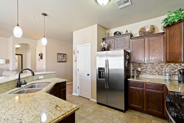 kitchen with arched walkways, a sink, visible vents, gas stove, and stainless steel refrigerator with ice dispenser