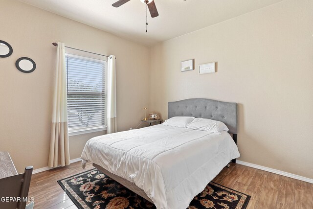 bedroom with ceiling fan, baseboards, and wood finished floors