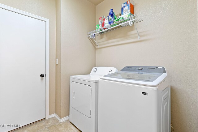 laundry room with washing machine and clothes dryer, laundry area, and light tile patterned flooring