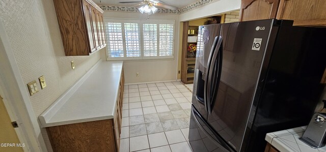 2704 Gaston Dr, El Paso, TX 79935 - kitchen with fridge with ice dispenser, brown cabinets, tile counters, light tile patterned floors, and ceiling fan
