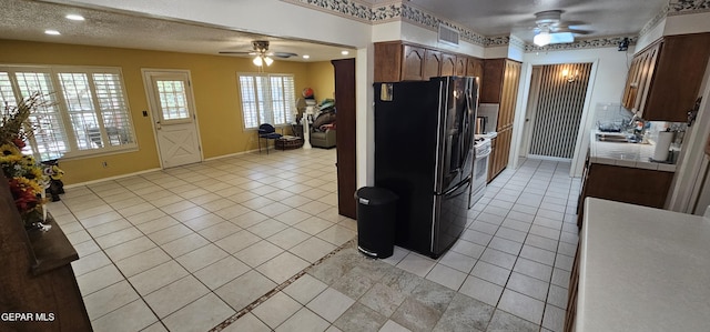 2704 Gaston Dr, El Paso, TX 79935 - kitchen featuring light tile patterned floors, ceiling fan, tile counters, and black fridge