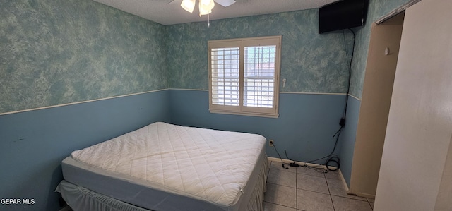 2704 Gaston Dr, El Paso, TX 79935 - bedroom featuring tile patterned flooring, ceiling fan, wallpapered walls, and a textured ceiling
