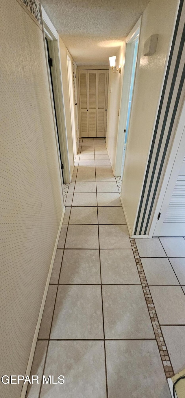 2704 Gaston Dr, El Paso, TX 79935 - hallway featuring baseboards, light tile patterned floors, and a textured ceiling