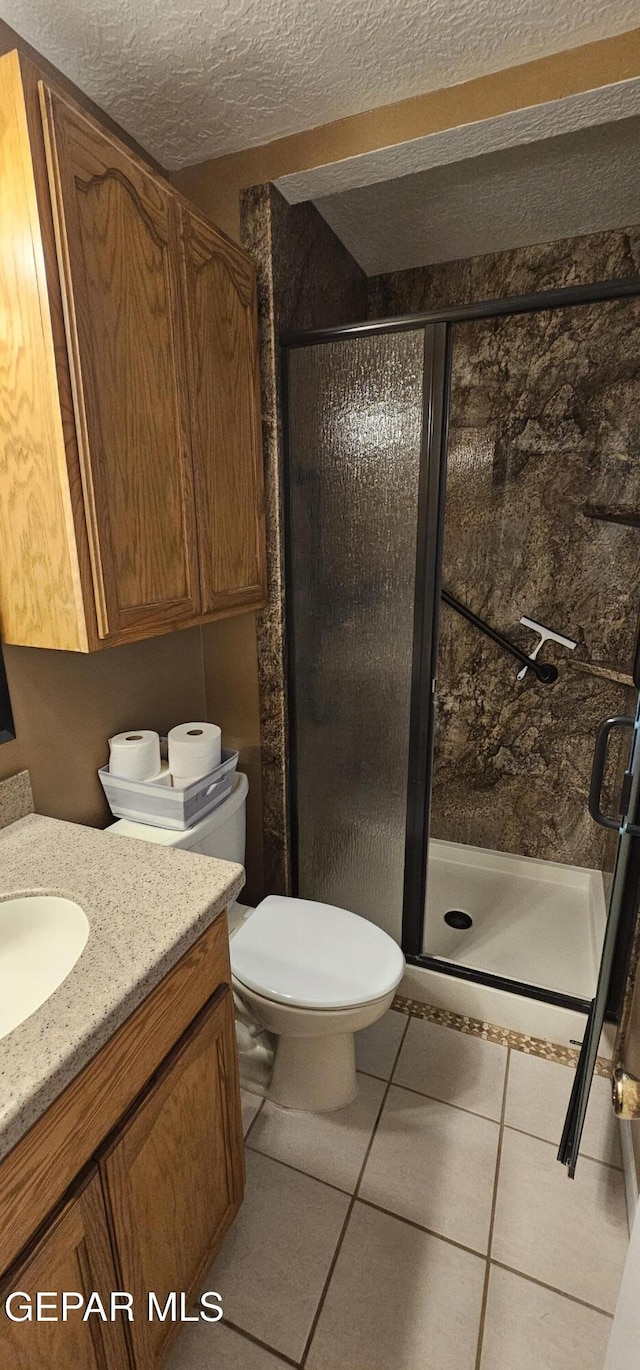 2704 Gaston Dr, El Paso, TX 79935 - bathroom with toilet, a shower stall, a textured ceiling, and vanity