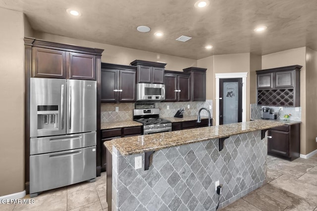 7229 Camino Del Sol Dr, El Paso, TX 79911 - kitchen featuring stainless steel appliances, light stone countertops, a breakfast bar, recessed lighting, and tasteful backsplash