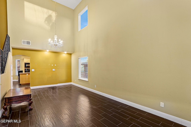 unfurnished living room featuring visible vents, arched walkways, baseboards, and a chandelier