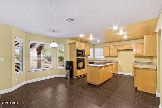 kitchen with baseboards, a center island, black appliances, and a textured ceiling