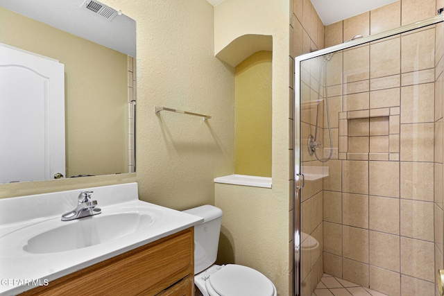 full bath with vanity, a shower stall, toilet, and visible vents