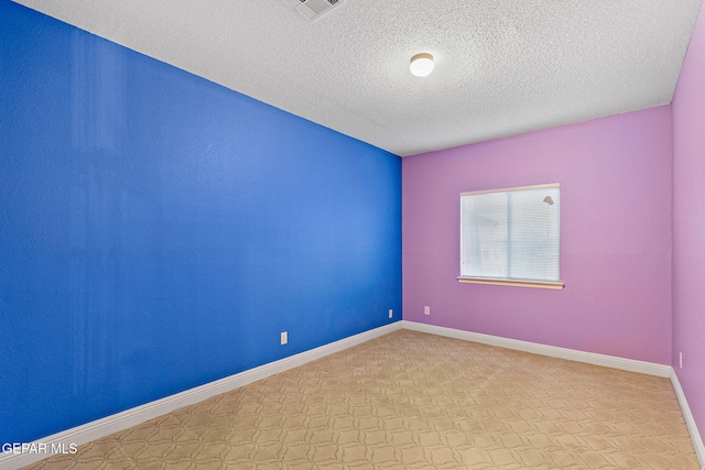 empty room with baseboards, light carpet, a textured ceiling, and visible vents