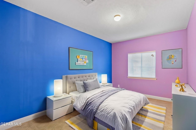 bedroom with a textured ceiling, baseboards, and visible vents