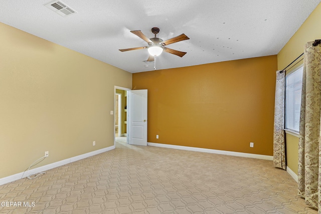 unfurnished room with baseboards, ceiling fan, a textured ceiling, and visible vents