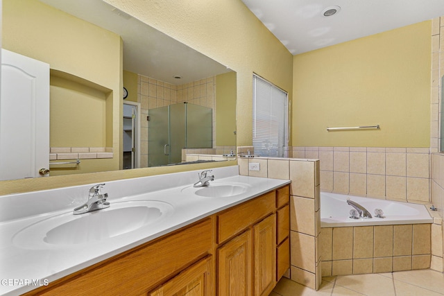 bathroom featuring tile patterned flooring, a sink, a garden tub, and a stall shower