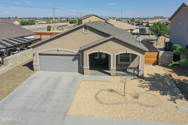 view of front of home with driveway, fence, a garage, stucco siding, and a residential view
